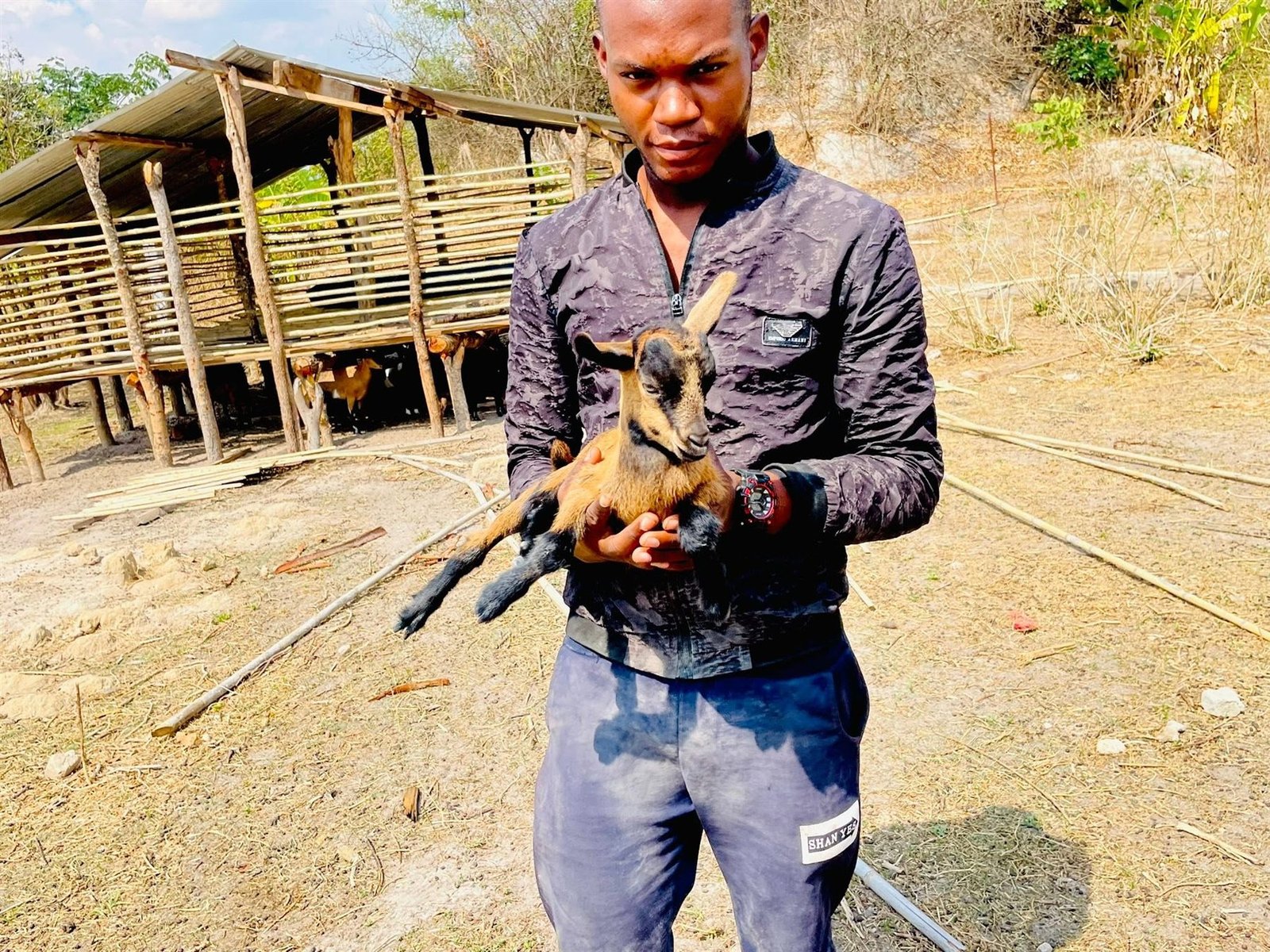 A Libarti Boys learner holding a young goat near the livestock shelter